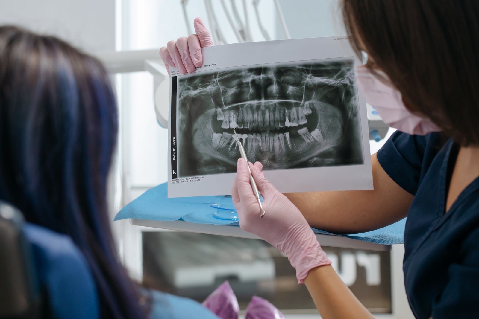 Profissional mostrando uma radiografia panorâmica a uma paciente